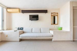 a living room with a white couch and a tv at Hermosa Villa Puesta al SOL in Acapulco
