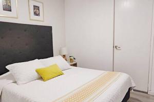 een slaapkamer met een wit bed en een geel kussen bij Leonora MaiaHome-Amplio apt en Polanco a pasos de Masaryk 3BD + 3BT in Mexico-Stad