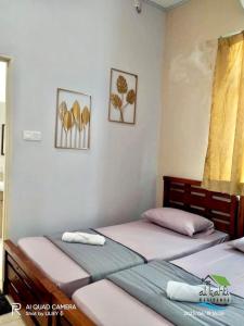 two twin beds in a bedroom with two pictures on the wall at Qalya Homestay 2 @ Kota Bharu in Kota Bharu