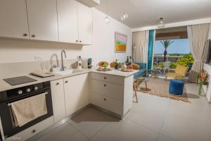 a kitchen with white cabinets and a living room at Mina's Suites - קיסריה in Caesarea