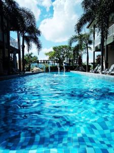 a large swimming pool with blue water and palm trees at Destini Akef Villa in Pantai Cenang
