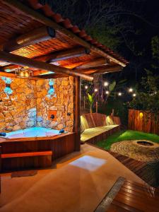 a hot tub on a patio with a stone wall at Chalés Araucária e Manacá in São Bento do Sapucaí