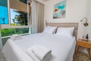 a bedroom with a bed with white sheets and a window at Mina's Suites - קיסריה in Caesarea