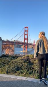 a woman on a skateboard in front of a bridge at ITH San Francisco Pacific Tradewinds Hostel in San Francisco