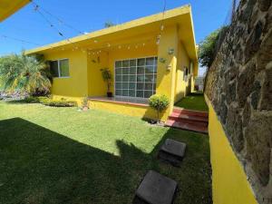 uma casa amarela com um quintal em frente em Hermosa casa de descanso, alberca privada, caldera em Oaxtepec