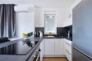 a kitchen with white cabinets and black counter tops at Vidalis, no 1 in Kožino