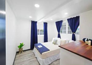 a white bedroom with blue curtains and a bed at The Rise South Coast Rental by On Point Property Management in Christ Church