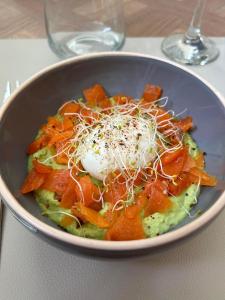 - un bol de nourriture avec des carottes et du fromage sur une table dans l'établissement chambre d'hôtes Le Domaine de la Vallée, à Saint-Martin-de-Varreville