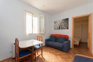 a living room with a table and a blue couch at Precioso Apartamento in Madrid