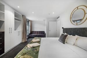 a bedroom with a large white bed and a couch at The Essence of Queenstown in Queenstown