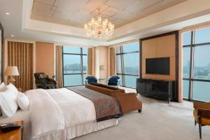 um quarto com uma cama grande e uma televisão de ecrã plano em The Westin Wuhan Wuchang em Wuhan