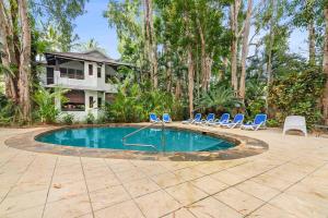 a swimming pool with chairs and a house at Palm Cove Treetop Spa Retreat in Palm Cove