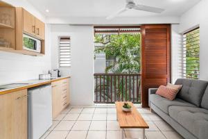 a kitchen and living room with a couch and a table at Palm Cove Treetop Spa Retreat in Palm Cove