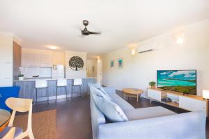 a living room with a couch and a kitchen at Coral Sea Vista Apartments in Airlie Beach