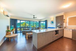 een open keuken en een woonkamer met een bank bij Coral Sea Vista Apartments in Airlie Beach