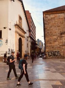 dwoje ludzi spacerujących ulicą w mieście w obiekcie A Moderno loft con wifi en Centro de Bogotá w mieście Bogota