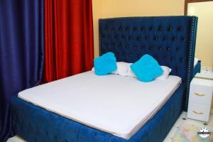 niebieskie łóżko z dwoma niebieskimi poduszkami w obiekcie Denverwing Homes. w mieście Eldoret