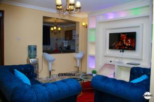 ein Wohnzimmer mit 2 blauen Sofas und einem TV in der Unterkunft Denverwing Homes. in Eldoret