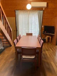 a dining room with a table and chairs and a television at コテージ　マリーゴールド in Nasu-yumoto