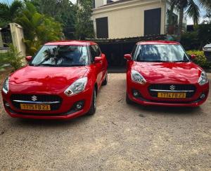 zwei rote Autos, die vor einem Haus geparkt sind in der Unterkunft Le Gite du Bonheur Guest House & Car Rental in Tamarin