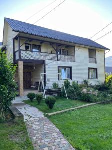 une maison blanche avec un chemin devant elle dans l'établissement садиба Сніжок, à Yaremtche