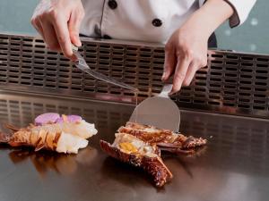 a person cutting up food on a counter with spatulas at Windsor Hotel Taichung in Taichung