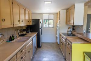 a kitchen with wooden cabinets and a black refrigerator at Designer Hideaway in Borrego Springs