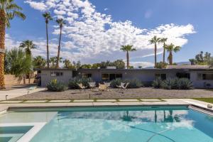 a swimming pool in front of a house with palm trees at Designer Hideaway in Borrego Springs