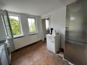 an empty kitchen with a refrigerator and two windows at Mehrere Zimmer in erster Lage in Siegen