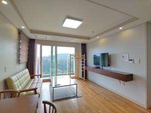 a living room with a couch and a television at Jeju Lavender Hotel in Seogwipo