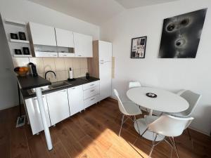 una cucina con mobili bianchi, tavolo e sedie di Apartment Mona Vir a Vir (Puntadura)