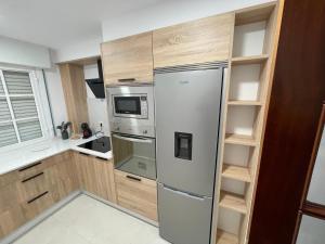 una cocina con nevera de acero inoxidable y armarios de madera en Apartamentos Demar Luis Casais en O Grove