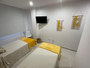 Habitación pequeña con 2 camas y TV. en Apartamentos Demar Luis Casais en O Grove