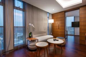 a living room with a couch and tables and windows at Novotel Shanghai Hongqiao in Shanghai