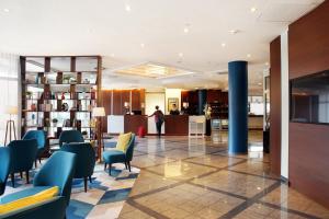 a lobby with blue chairs and a person in the background at Courtyard by Marriott Dresden in Dresden