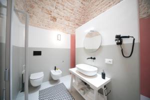 a bathroom with a sink and a toilet and a mirror at San Marco Boutique Rooms in Alberobello