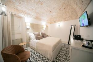 1 dormitorio con 1 cama, TV y silla en San Marco Boutique Rooms en Alberobello