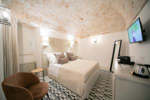 1 dormitorio con 1 cama, TV y silla en San Marco Boutique Rooms, en Alberobello