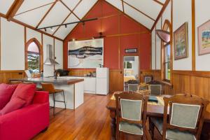 a kitchen and living room with a red couch and a table at The Chapel- Kohukohu in Kohukohu Town District