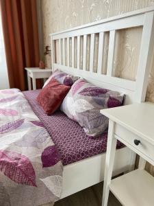 een wit bed met paarse kussens en een tafel bij White Deluxe Apartments in Chernihiv