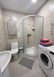 een badkamer met een douche, een toilet en een wasmachine bij White Deluxe Apartments in Chernihiv
