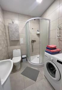 y baño con ducha, aseo y lavadora. en White Deluxe Apartments, en Cherníhiv