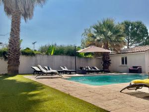 a swimming pool with lounge chairs and an umbrella at Villa 11 personnes in Saturargues