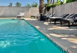 a swimming pool with lounge chairs and a table and chairs at Villa 11 personnes in Saturargues