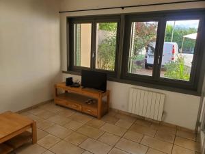 a living room with a tv and two windows at T2 idéalement situé in Thonon-les-Bains