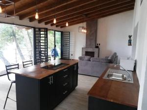 cocina y sala de estar con mesa y sofá en Zirahuen, cabaña moderna junto al lago, en Zirahuén