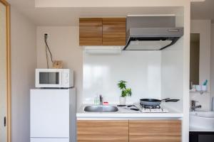 een keuken met een witte koelkast en een magnetron bij Rewitビル in Osaka