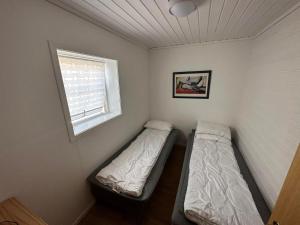 two beds in a small room with a window at Nautnes Seaside Apartments in Nautnes