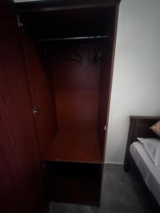 um armário de madeira ao lado de uma cama num quarto em N Joy Inn em Trincomalee