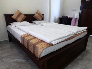 uma cama grande com lençóis brancos e almofadas em N Joy Inn em Triquinimale